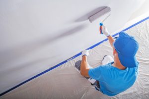 House Painting Contractor with drop cloth and blue tapered wall