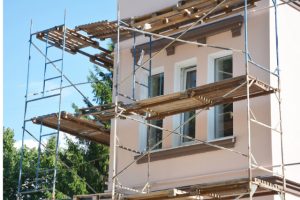 Painting and Plastering Exterior House with scaffolding and wood planks